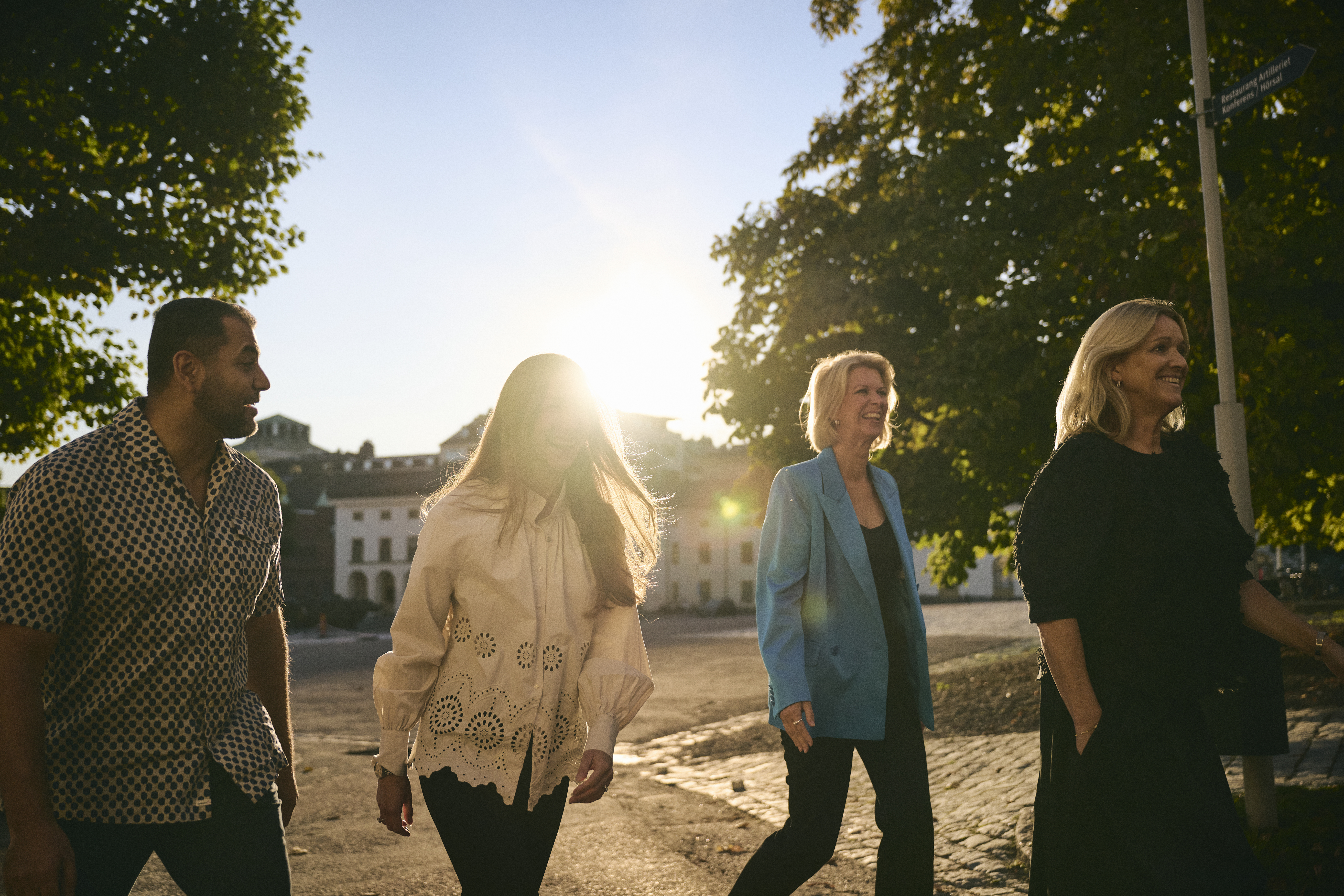 Glada kollegor promenerar skrattande tillsammans utomhus en solig sommarkväll.