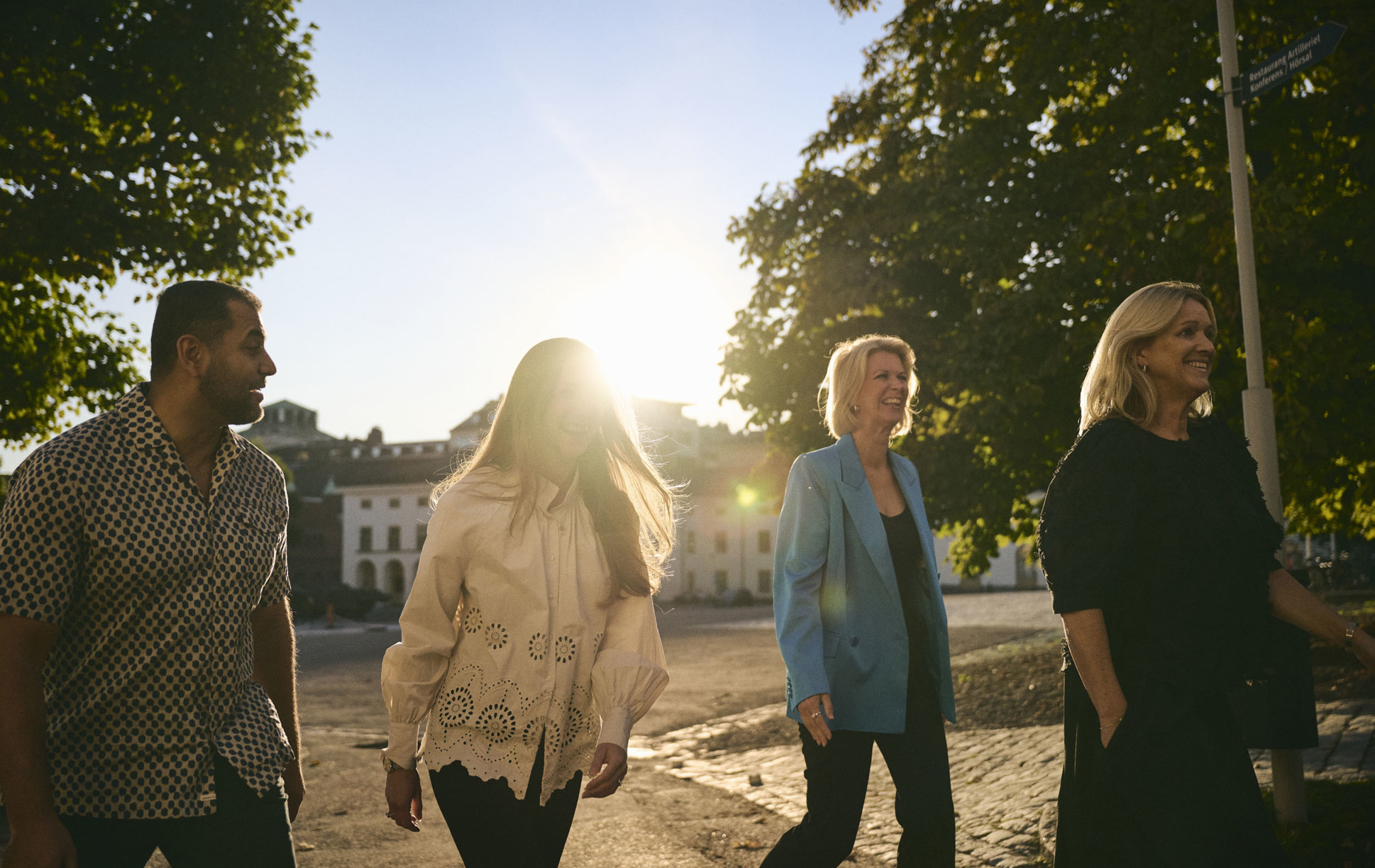 En grupp människor som vistas utomhus med solen som skiner och ett slott i bakgrunden.